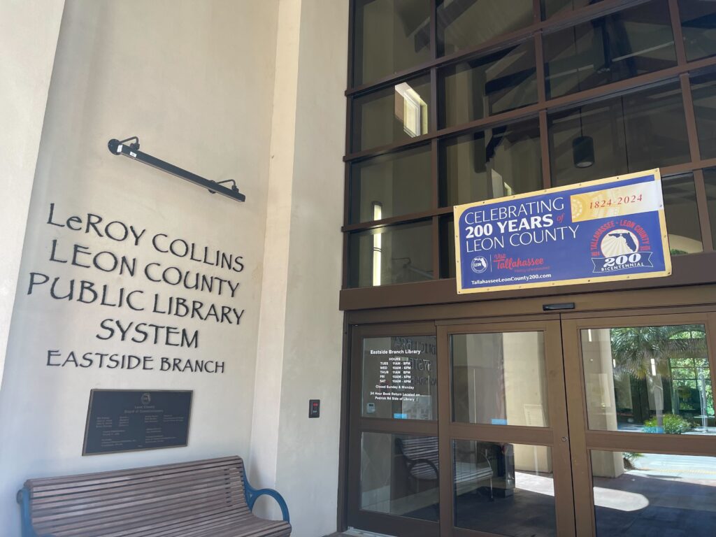 East Side Branch of Leroy Collins Leon County Public Library entrance, featuring high ceiling white wall and floor to ceiling glass door and windows for the entry