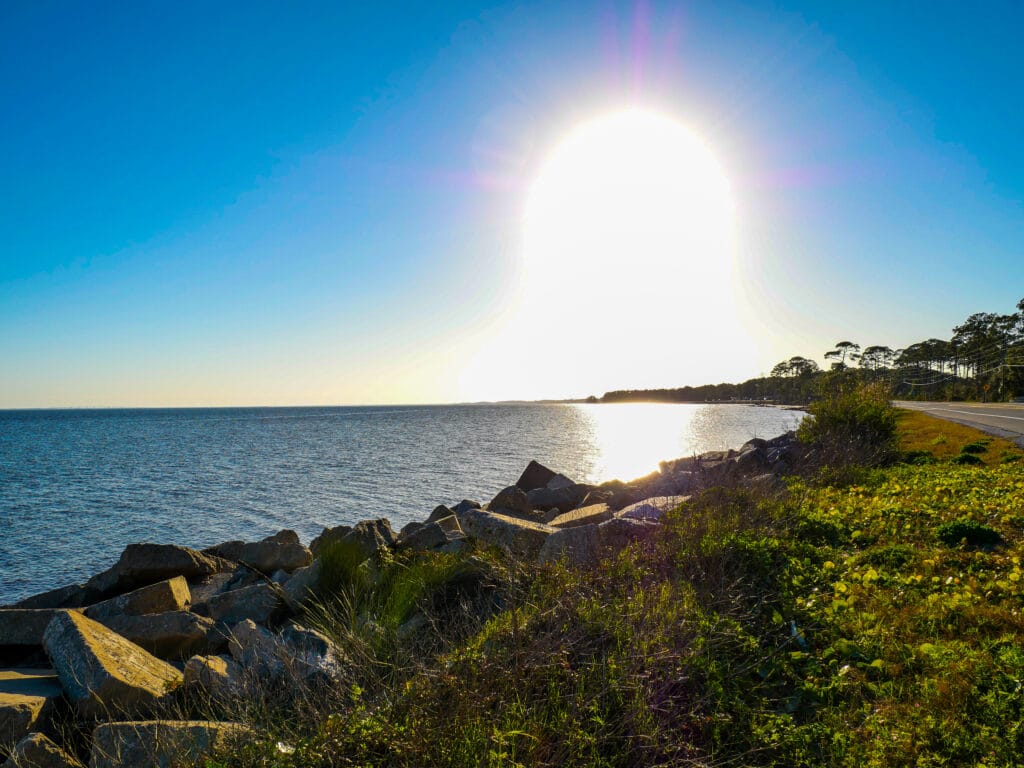 A side view of the beach with the sun beaming