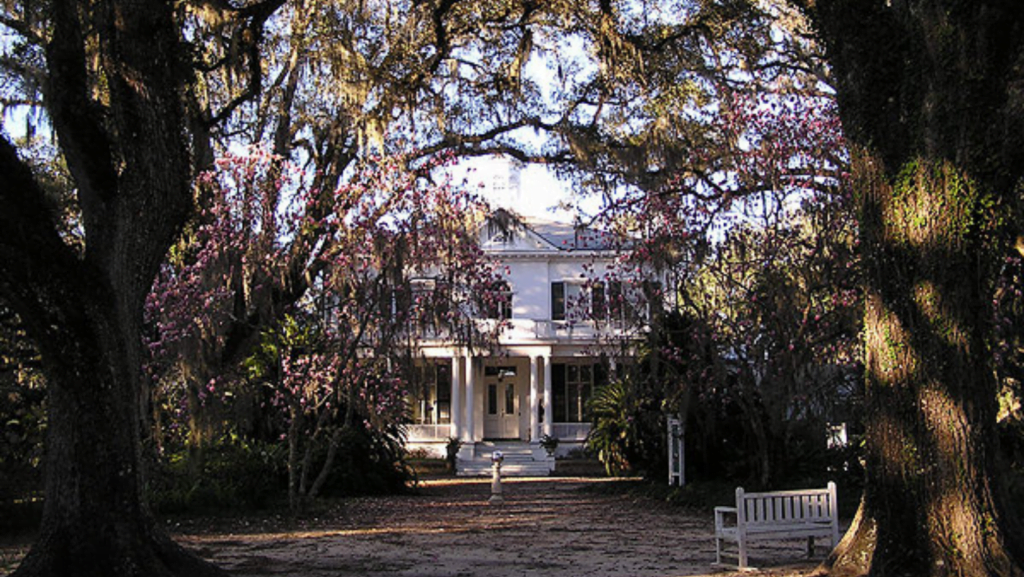Photo of the main house at the Goodwood Museum and Gardens with trees surrounding it.