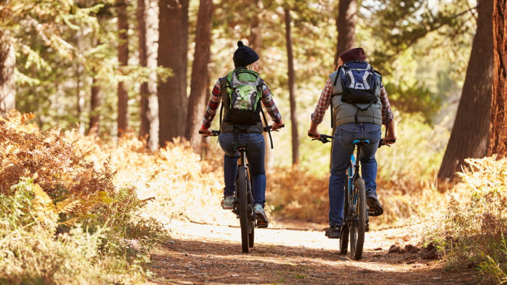 A couple biking on an outdoor trail in northwest florida on a sunny day, peddling away from the viewer