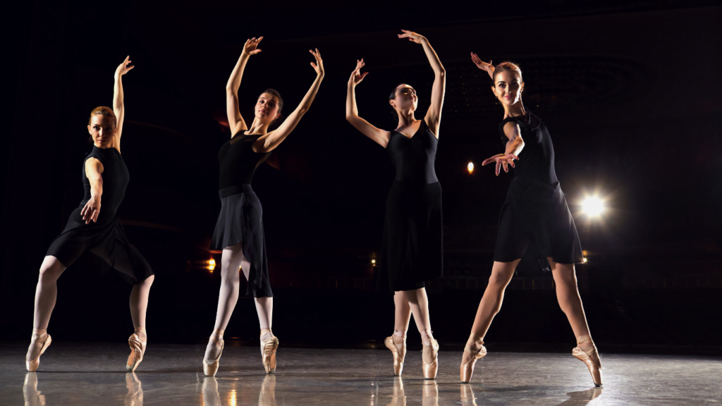 4 ballerinas on stage in black, in motion, dancing, with low lighting